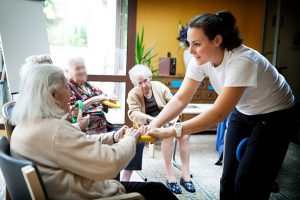 Séance de gym pour personnes âgées organisée par une animatrice en maison de retraite