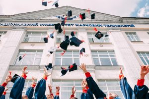 Groupe de jeunes diplômés qui jettent leur toque d'étudiant en l'air