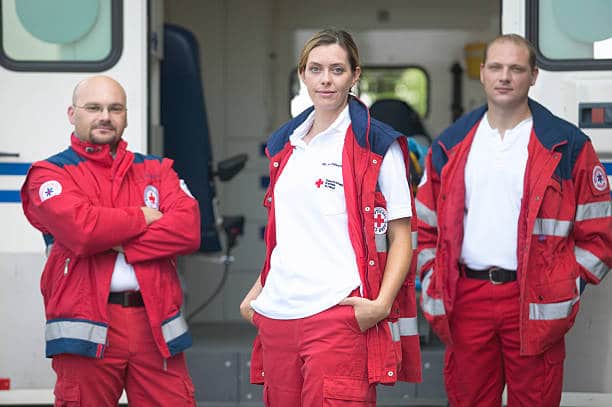 Equipe d'ambulanciers debout devant leur ambulance